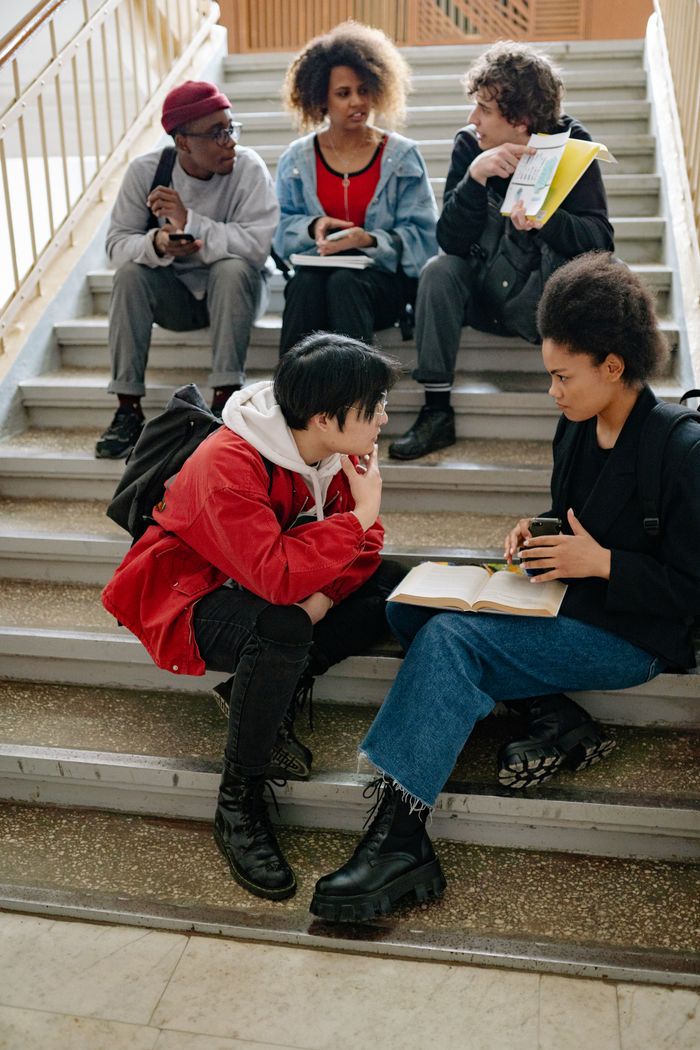Home A diverse group of students studying together on indoor stairs, promoting collaboration.